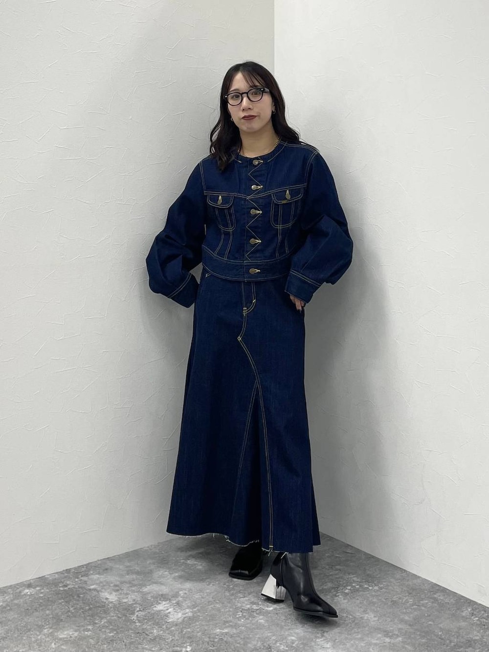 ブルー系のデニムジャケット、ブラック系のブーツ、ブルー系のデニムスカートを着用したレディースの秋コーディネートの2枚目の写真