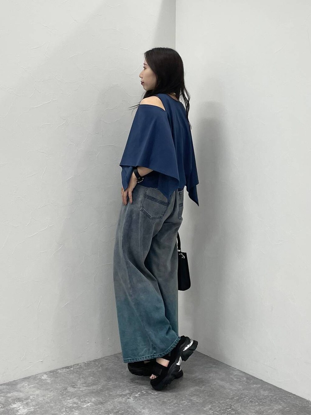 ブルー系のデニムパンツ、ブラック系のショルダーバッグ、ブラック系のサンダルを着用したレディースの夏コーディネートの2枚目の写真