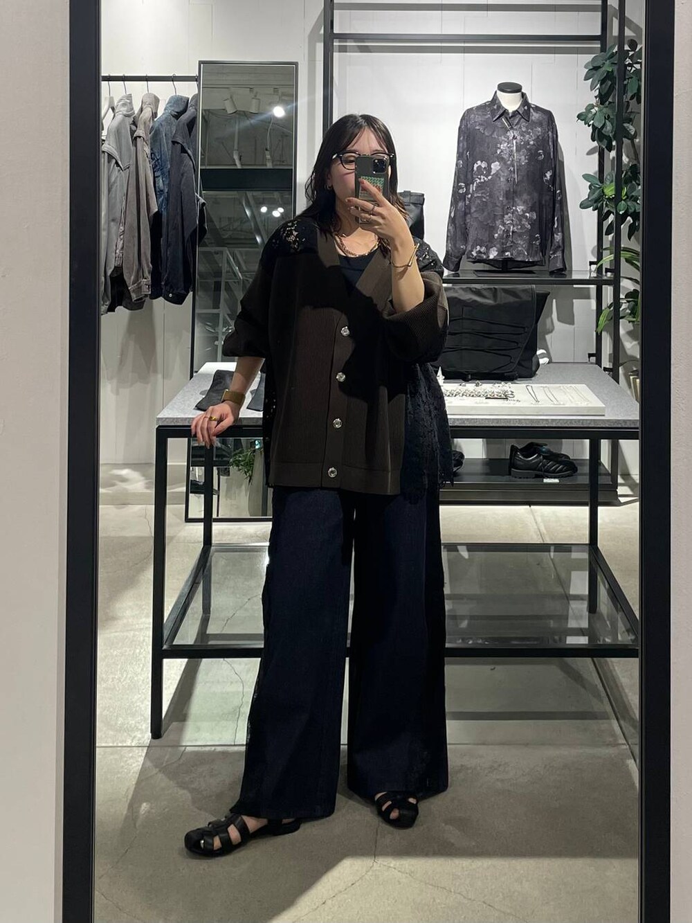 ブラック系のサンダル、ブラウン系のカーディガン/ボレロ、ブルー系のデニムパンツを着用したレディースの夏コーディネートの2枚目の写真