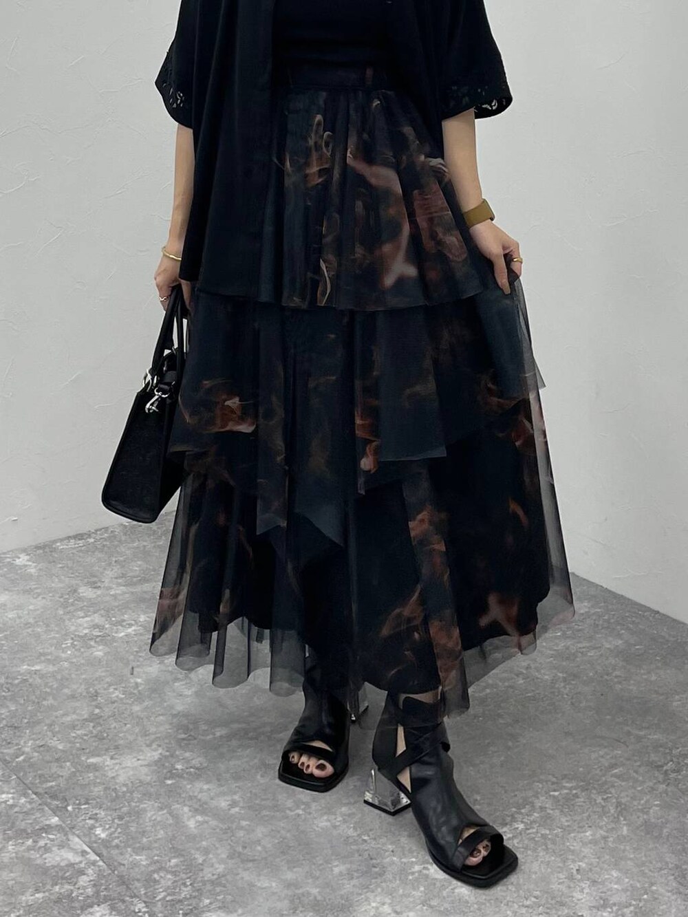 ブラック系のサンダル、ブラック系のショルダーバッグ、オレンジ系のスカートを着用したレディースの夏コーディネートの5枚目の写真