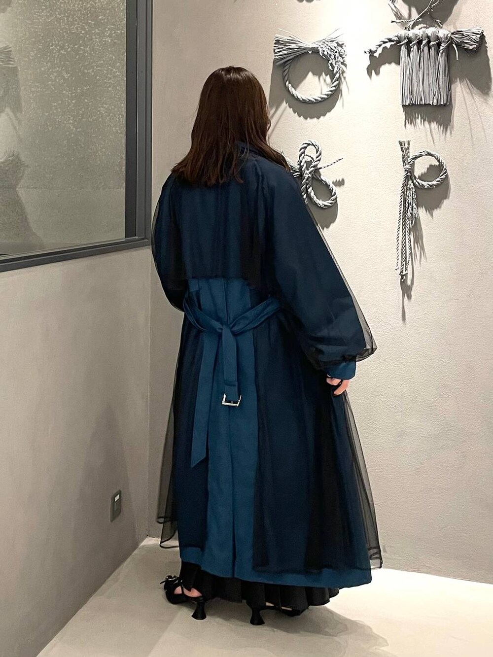 ブラック系のスカート、ブラック系のパンプス、ブルー系のトレンチコートを着用したレディースの秋コーディネートの2枚目の写真