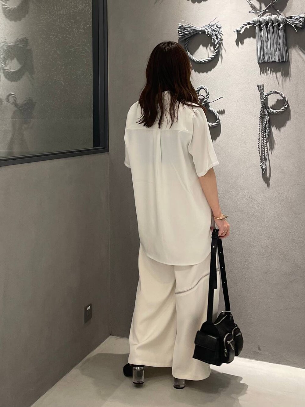 ブラック系のサンダル、ホワイト系のシャツ/ブラウス、ブラック系のショルダーバッグを着用したレディースの夏コーディネートの2枚目の写真