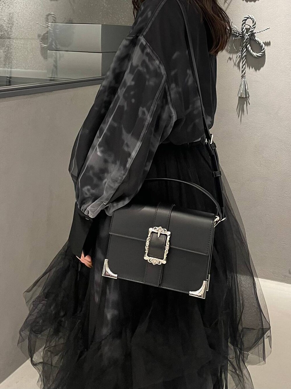 ブラック系のブーツ、ブラック系のショルダーバッグ、ブラック系のスカートを着用したレディースの冬コーディネートの6枚目の写真