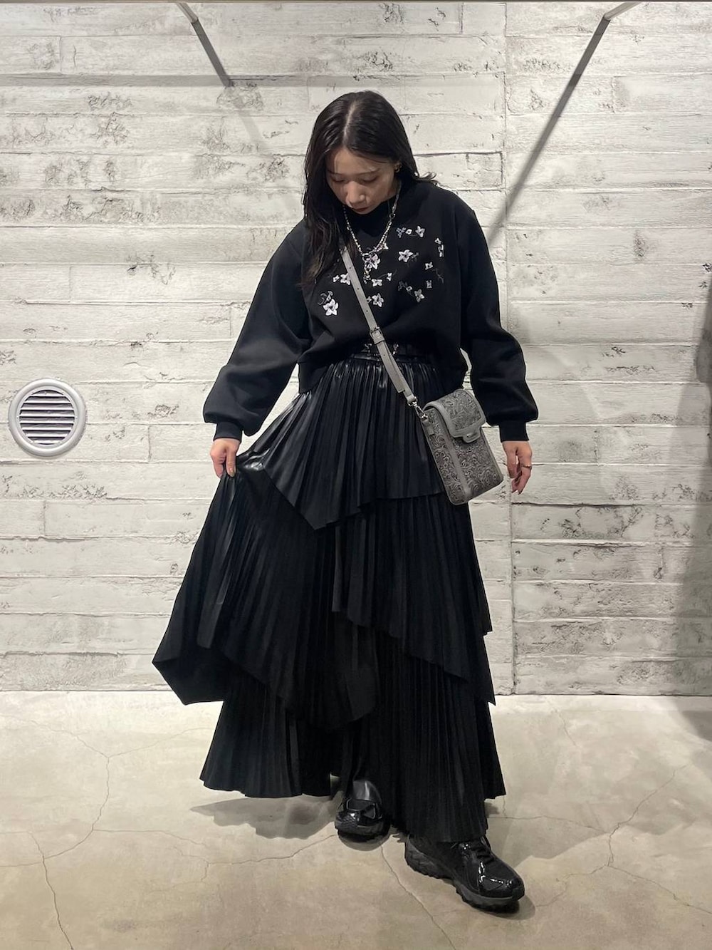 ブラック系のスウェット、グレー系のショルダーバッグ、ブラック系のスカートを着用したレディースの冬コーディネートの2枚目の写真