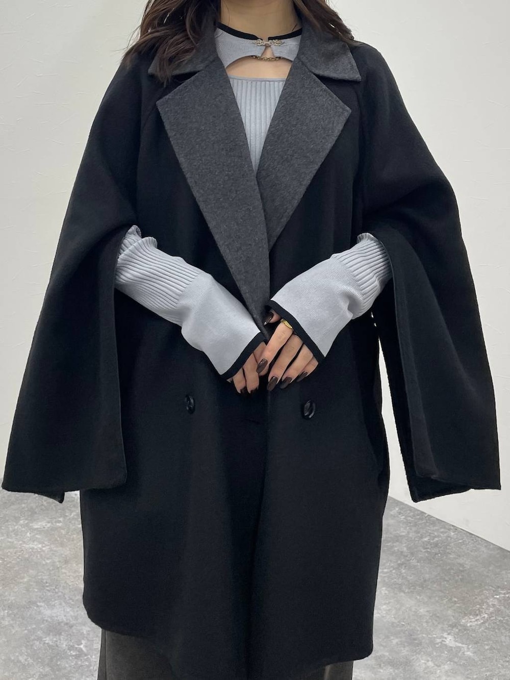 グレー系のニット/セーター、ブラック系のチェスターコート、ブラック系のブーツを着用したレディースの秋コーディネートの5枚目の写真