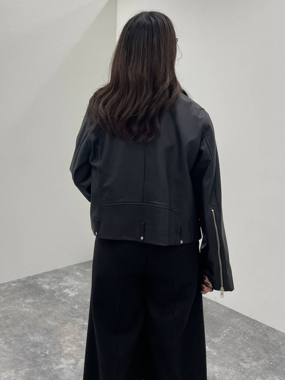 ブラック系のTシャツ/カットソー、ブラック系のライダースジャケット、ブラック系のスラックスを着用したレディースの秋コーディネートの5枚目の写真