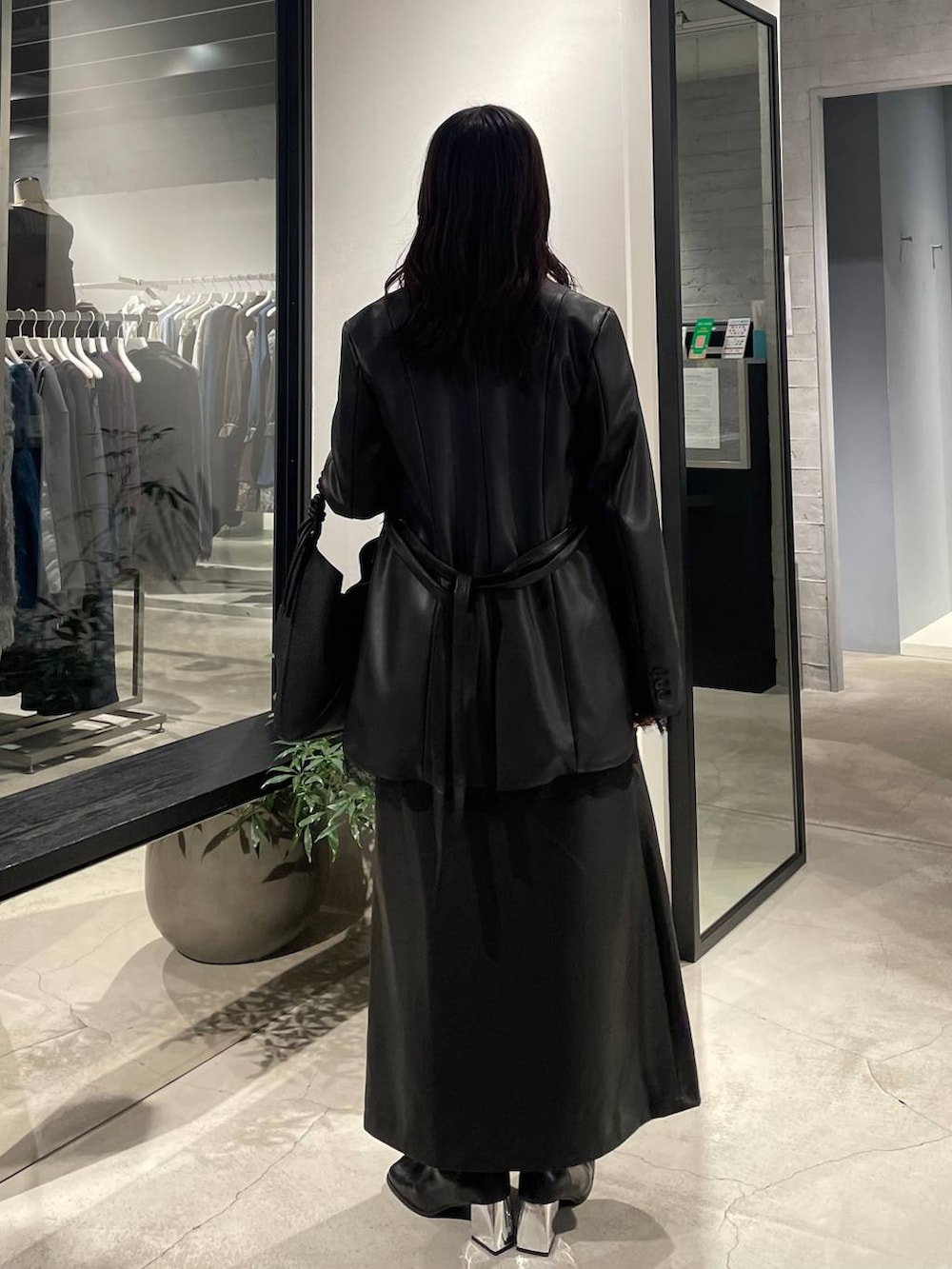 グレー系のニット/セーター、ブラック系のスカート、ブラック系のテーラードジャケットを着用したレディースの秋コーディネートの3枚目の写真