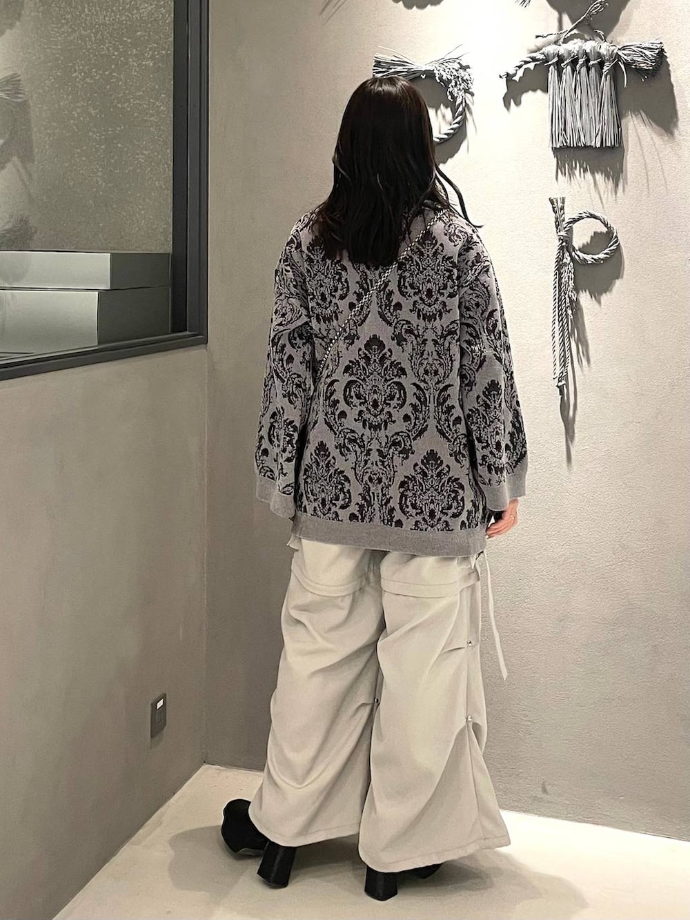 ホワイト系のカーゴパンツ、ブラック系のブーツ、グレー系のニット/セーターを着用したレディースの冬コーディネートの3枚目の写真
