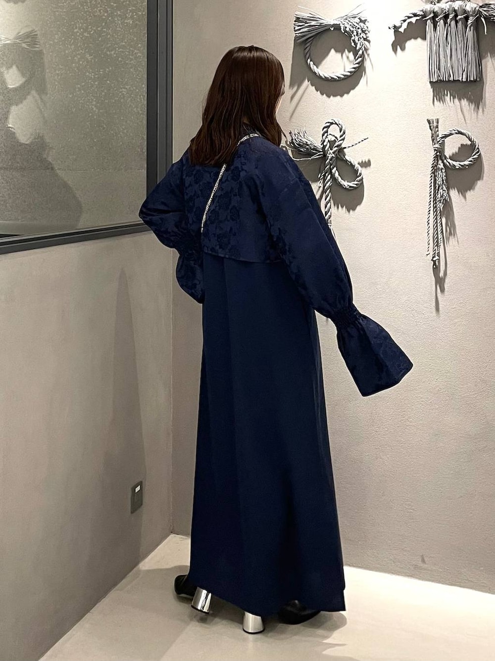 ブラック系のブーツ、ブルー系のワンピース、ブラック系の財布を着用したレディースの秋コーディネートの3枚目の写真