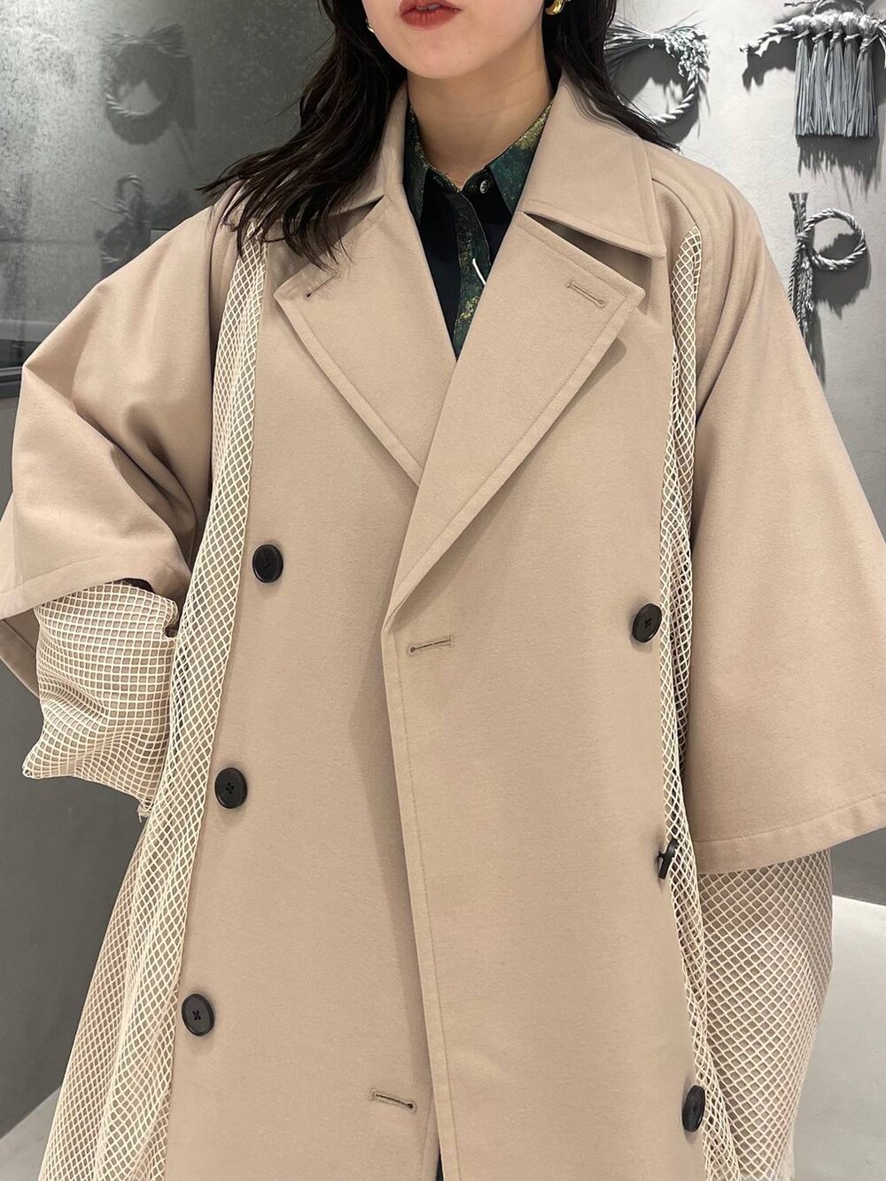 イエロー系のスカート、ブラック系のブーツ、ホワイト系のトレンチコートを着用したレディースの冬コーディネートの5枚目の写真