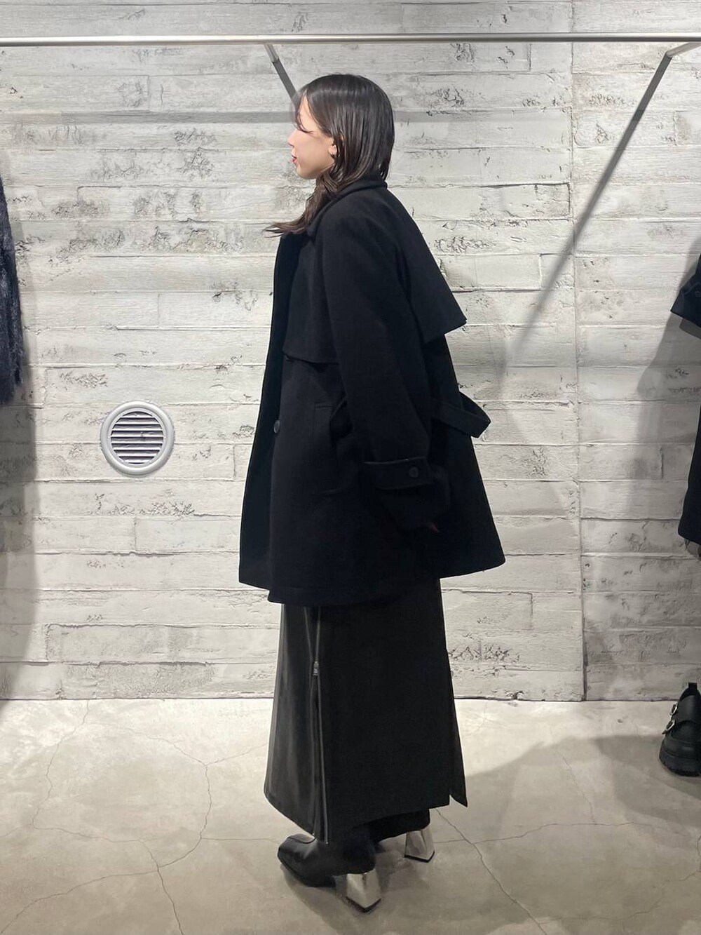 ブラック系のトレンチコート、ブラック系のブーツ、レッド系のニット/セーターを着用したレディースの秋コーディネートの3枚目の写真