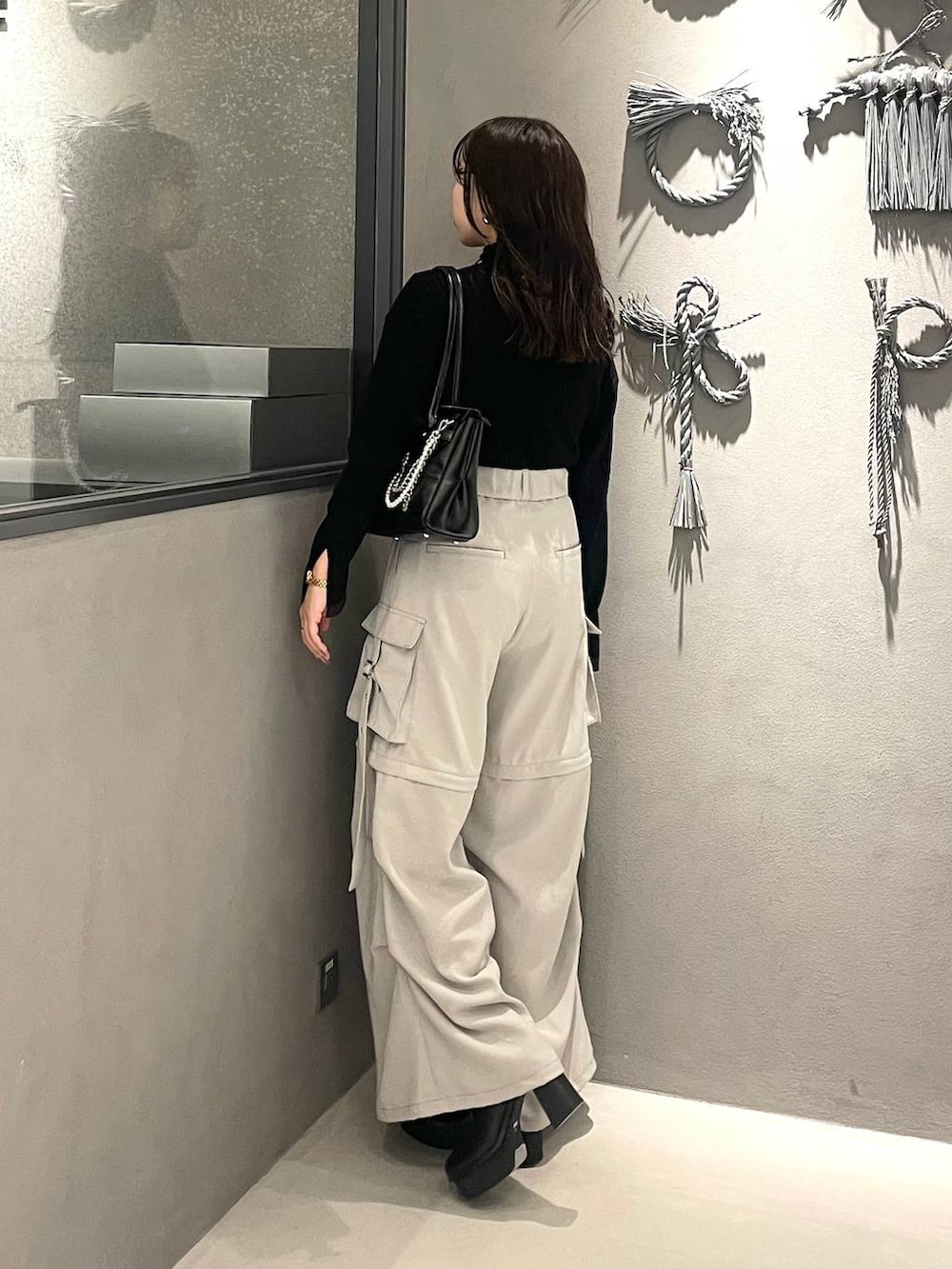 ホワイト系のカーゴパンツ、ブラック系のブーツ、ブラック系のボストンバッグを着用したレディースの冬コーディネートの2枚目の写真