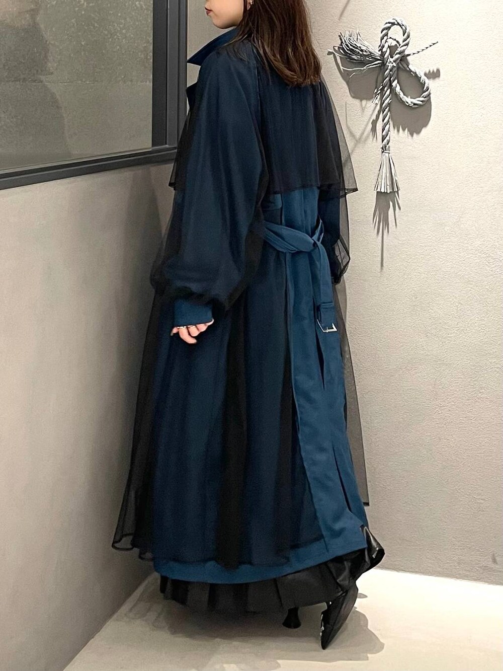 ブラック系のスカート、ブラック系のパンプス、ブルー系のトレンチコートを着用したレディースの秋コーディネートの3枚目の写真