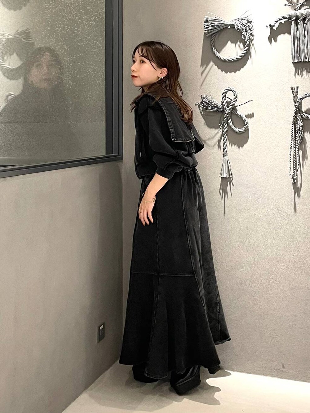 ブラック系のタンクトップ、ブラック系のブーツ、ブラック系のスカートを着用したレディースの秋コーディネートの2枚目の写真