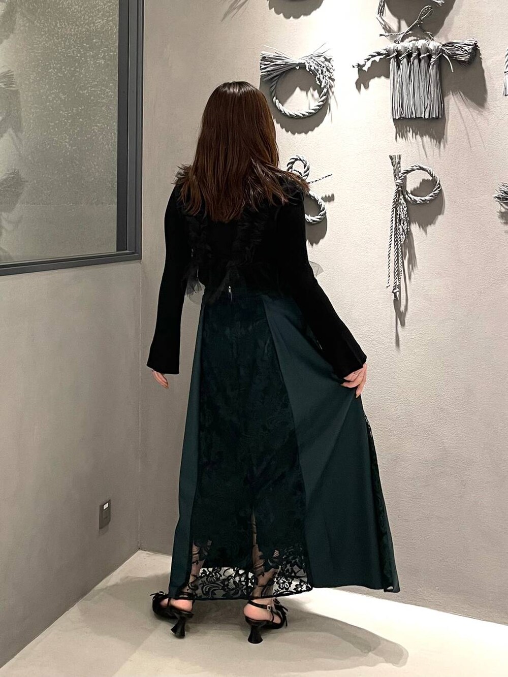 ブラック系のパンプス、ブラック系のニット/セーター、グリーン系のスカートを着用したレディースの夏コーディネートの2枚目の写真