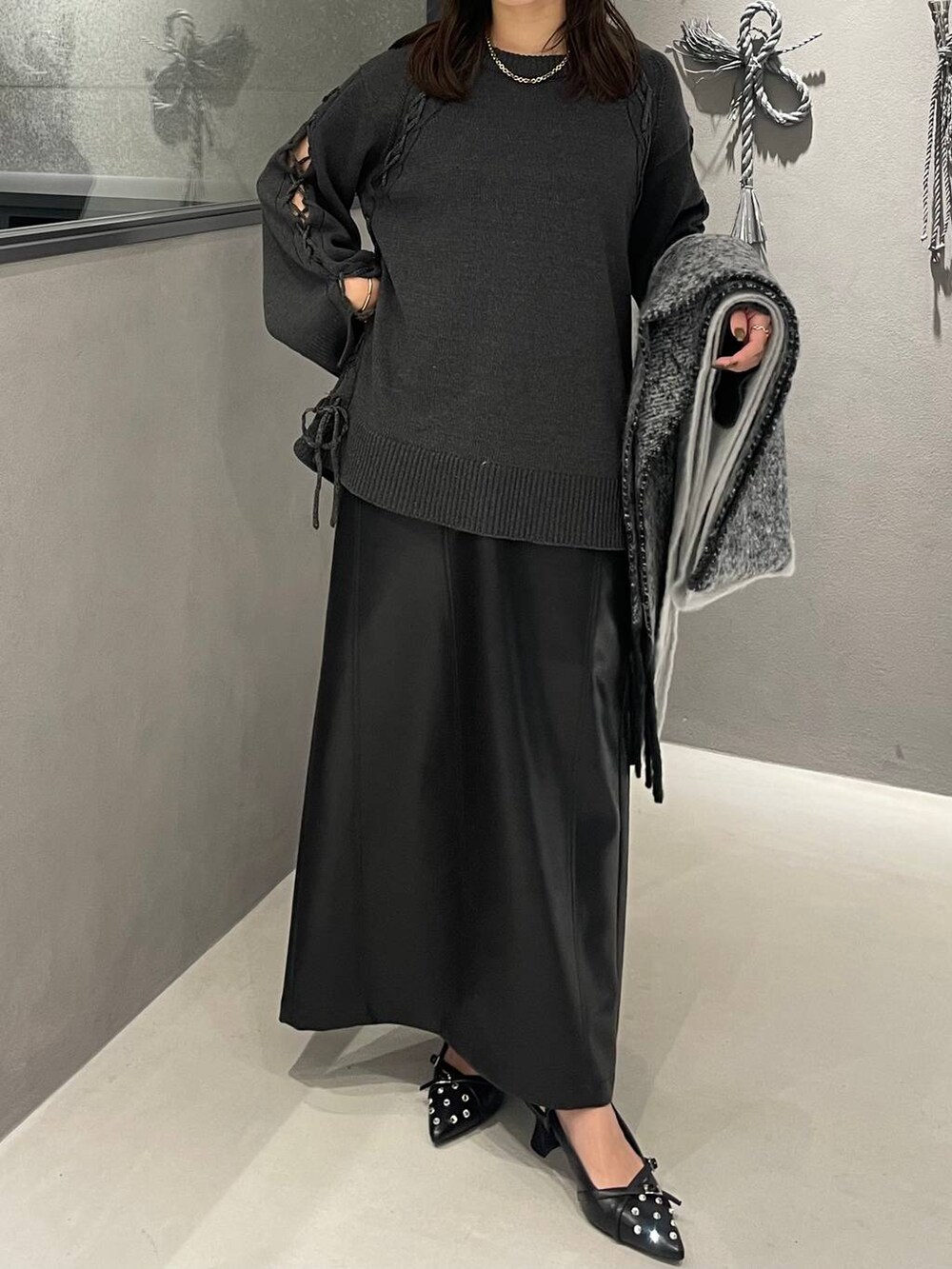 ブラック系のパンプス、グレー系のニット/セーター、ブラック系のスカートを着用したレディースの秋コーディネートの4枚目の写真