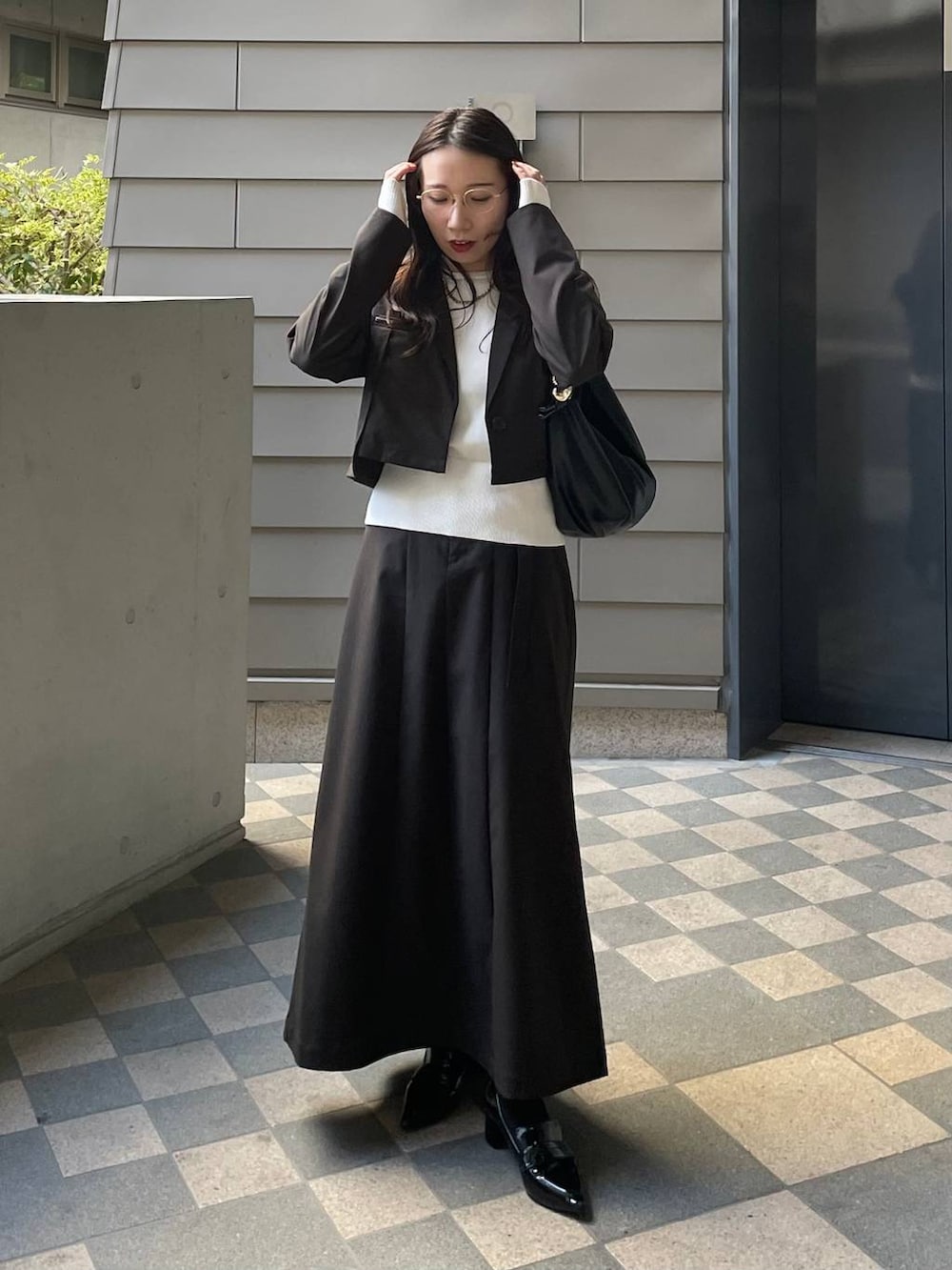 ブラック系のショルダーバッグ、ブラウン系のテーラードジャケット、ブラウン系のスカートを着用したレディースの冬コーディネートの2枚目の写真