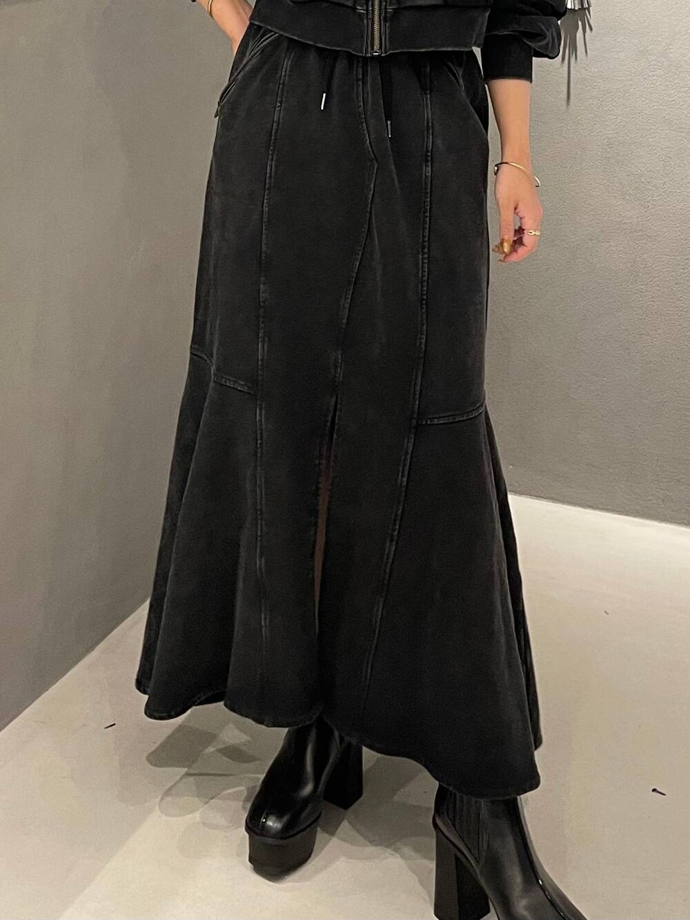 ブラック系のタンクトップ、ブラック系のブーツ、ブラック系のスカートを着用したレディースの秋コーディネートの6枚目の写真