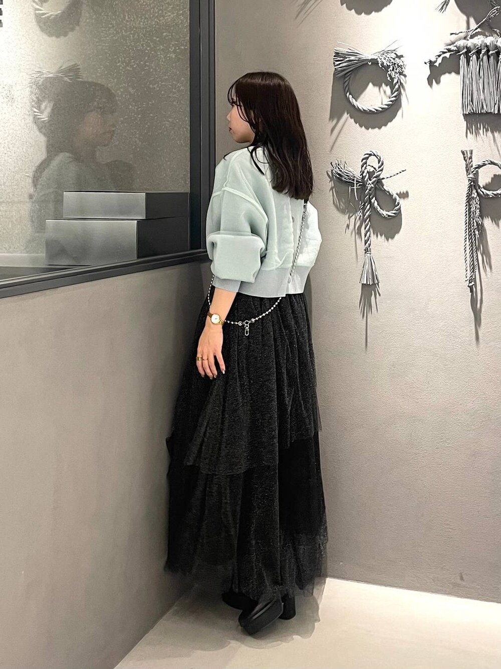 ブラック系のブーツ、グリーン系のカーディガン/ボレロ、ブラック系のスカートを着用したレディースの冬コーディネートの2枚目の写真