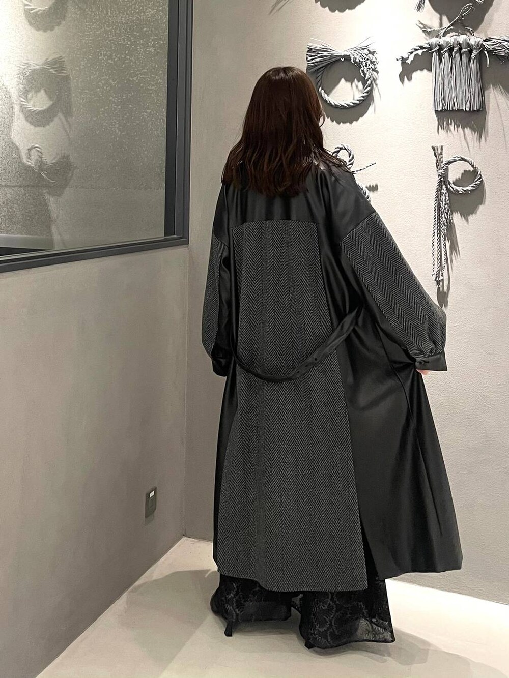 グレー系のチェスターコート、ブラック系のブーツ、ブルー系のニット/セーターを着用したレディースの秋コーディネートの3枚目の写真