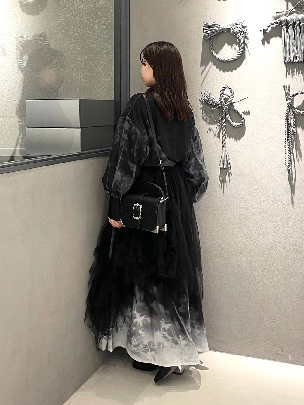 ブラック系のブーツ、ブラック系のショルダーバッグ、ブラック系のスカートを着用したレディースの冬コーディネートの2枚目の写真