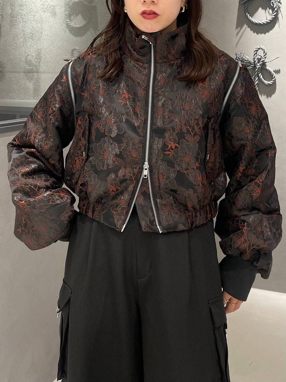 オレンジ系のブルゾン、ブラック系のブーツ、ブラック系のニット/セーターを着用したレディースの秋コーディネートの4枚目の写真