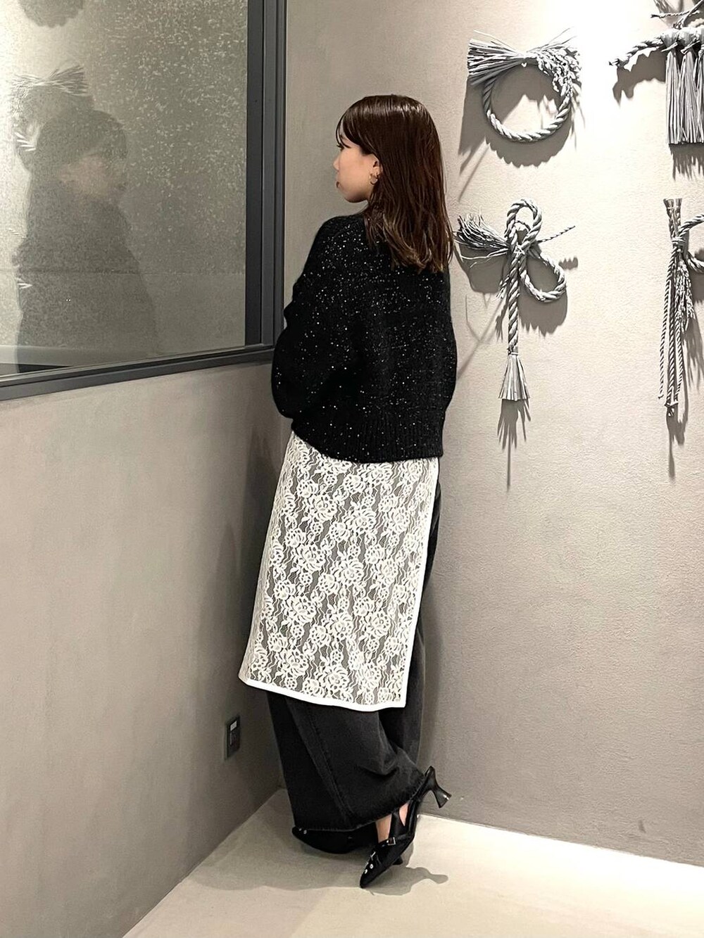 ブラック系のパンプス、ブラック系のニット/セーター、ブラック系のデニムパンツを着用したレディースの秋コーディネートの2枚目の写真