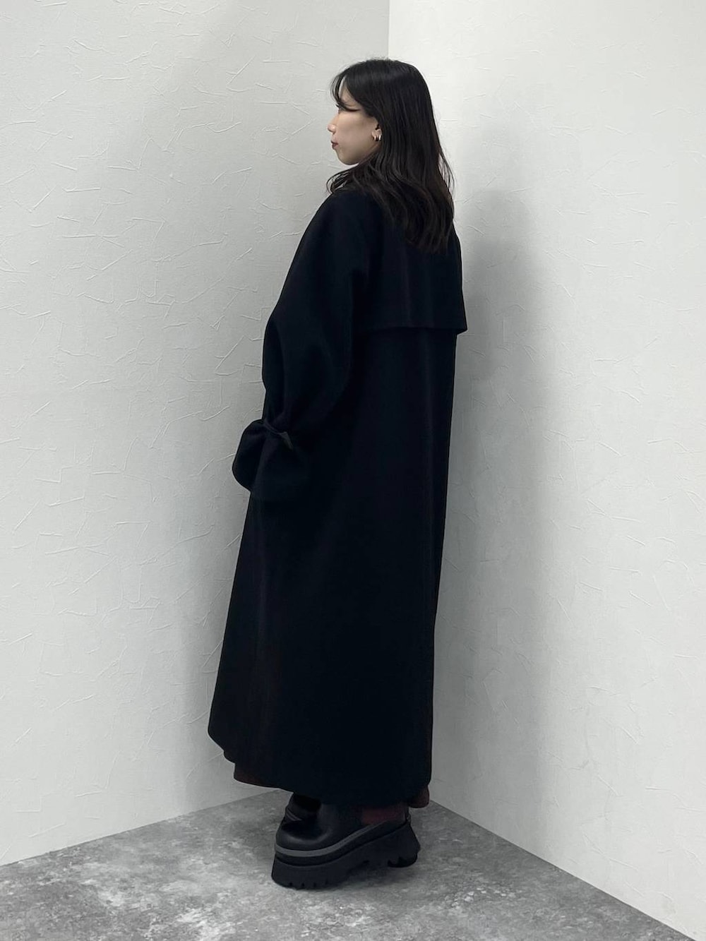 ブラック系のステンカラーコート、ブラック系のショルダーバッグ、レッド系のワンピースを着用したレディースの冬コーディネートの3枚目の写真