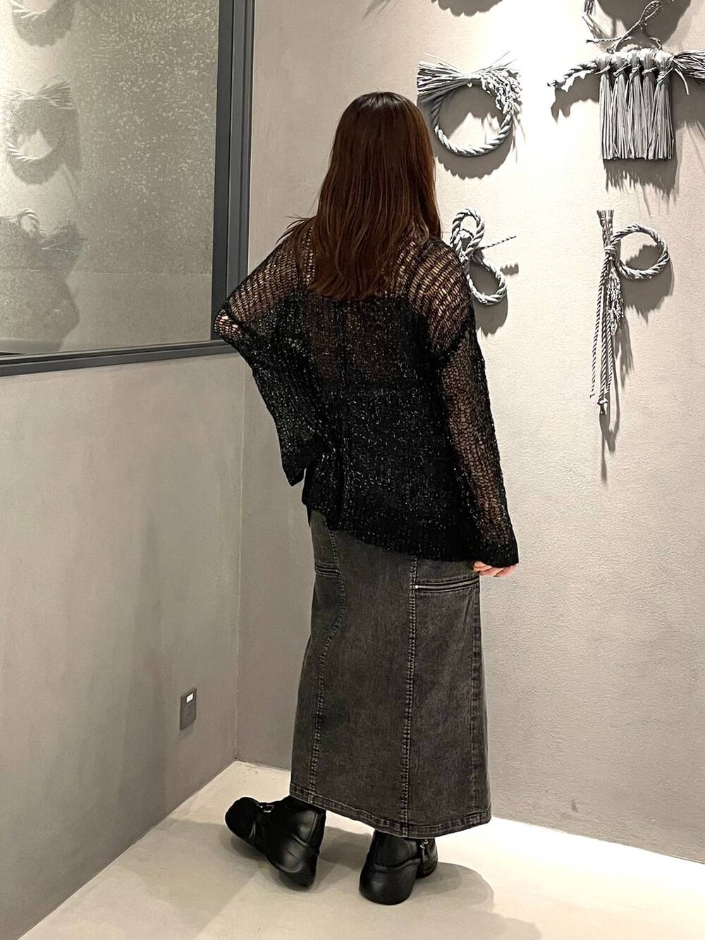 ブラック系のブーツ、ブラック系のニット/セーター、ブラック系のスカートを着用したレディースの夏コーディネートの2枚目の写真