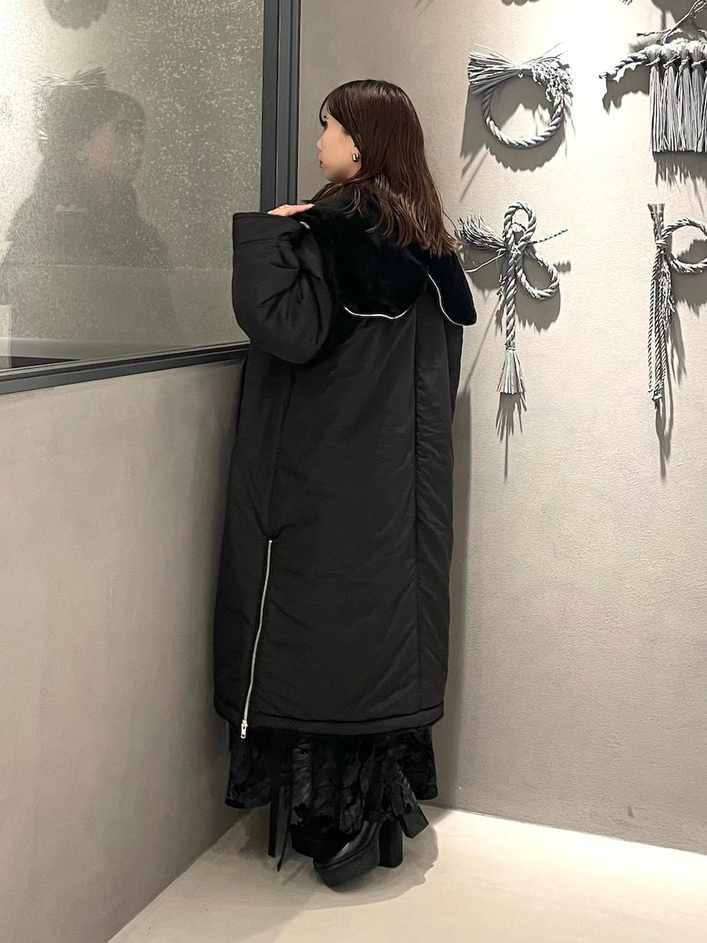 ブラック系のダウンジャケット/コート、ブラック系のブーツ、ブラック系のニット/セーターを着用したレディースの秋コーディネートの2枚目の写真