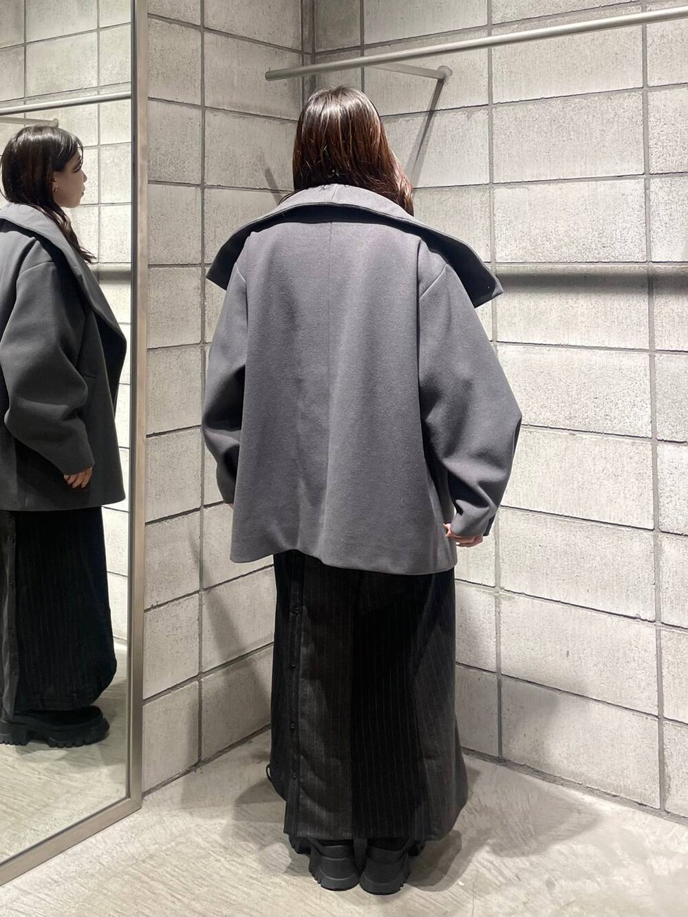 グレー系のチェスターコート、ブラウン系のカーディガン/ボレロ、グレー系のスカートを着用したレディースの冬コーディネートの4枚目の写真