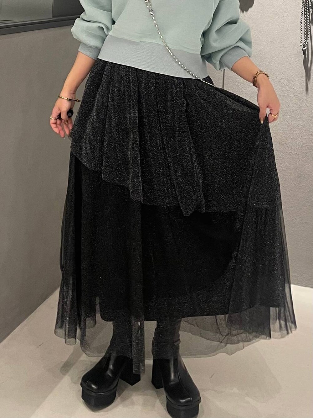 ブラック系のブーツ、グリーン系のカーディガン/ボレロ、ブラック系のスカートを着用したレディースの冬コーディネートの5枚目の写真