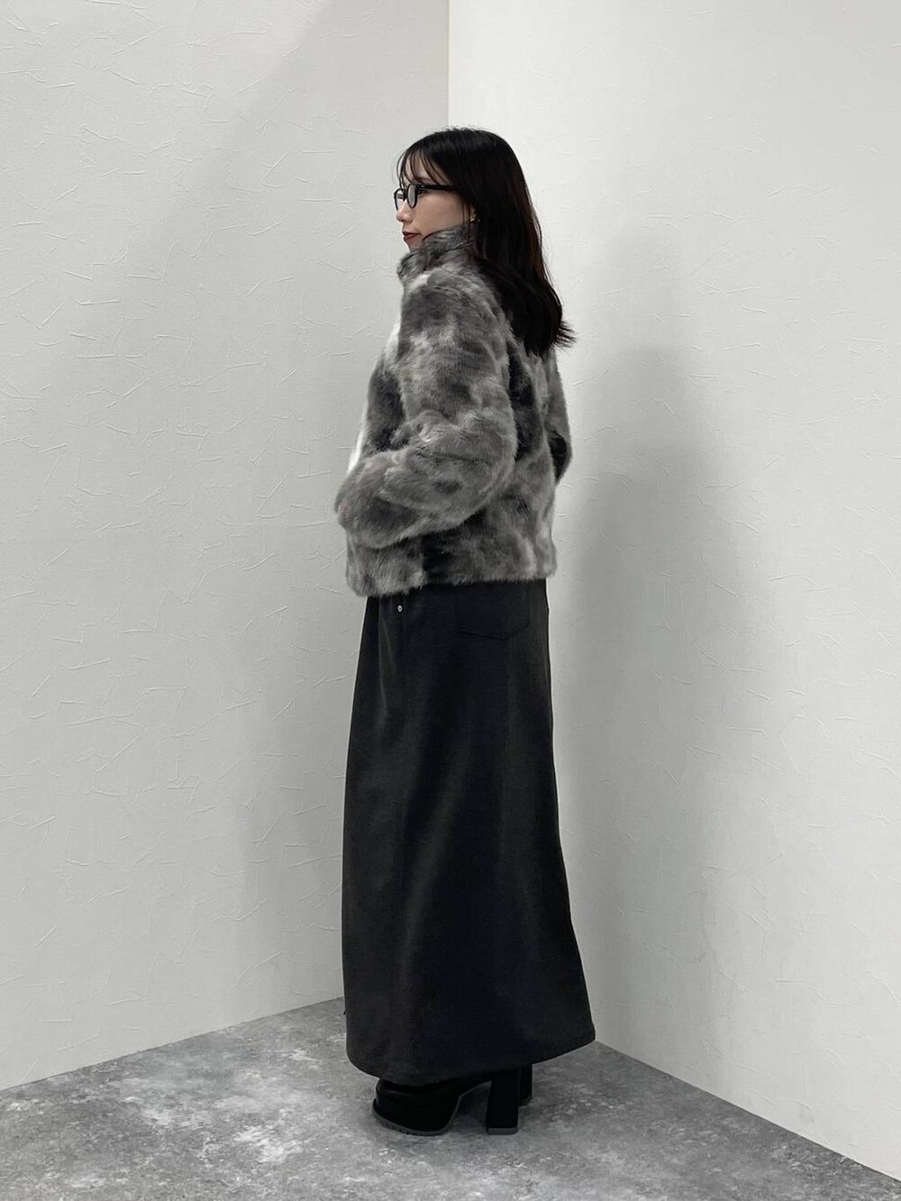 グレー系のブルゾン、ブラック系のブーツ、グレー系のスカートを着用したレディースの秋コーディネートの2枚目の写真