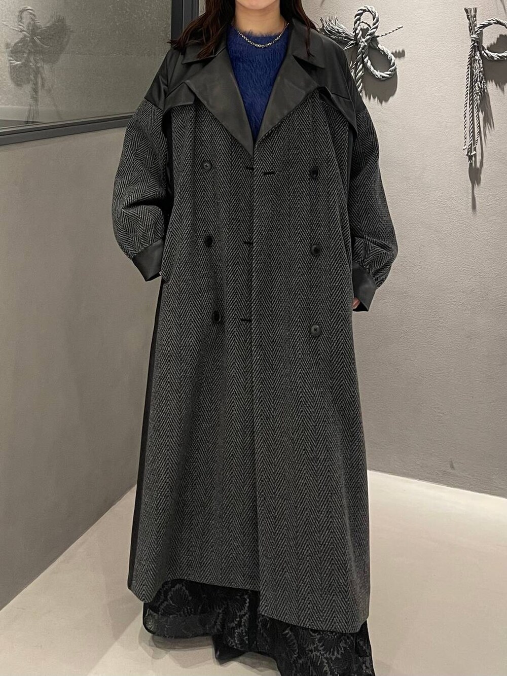 グレー系のチェスターコート、ブラック系のブーツ、ブルー系のニット/セーターを着用したレディースの秋コーディネートの4枚目の写真