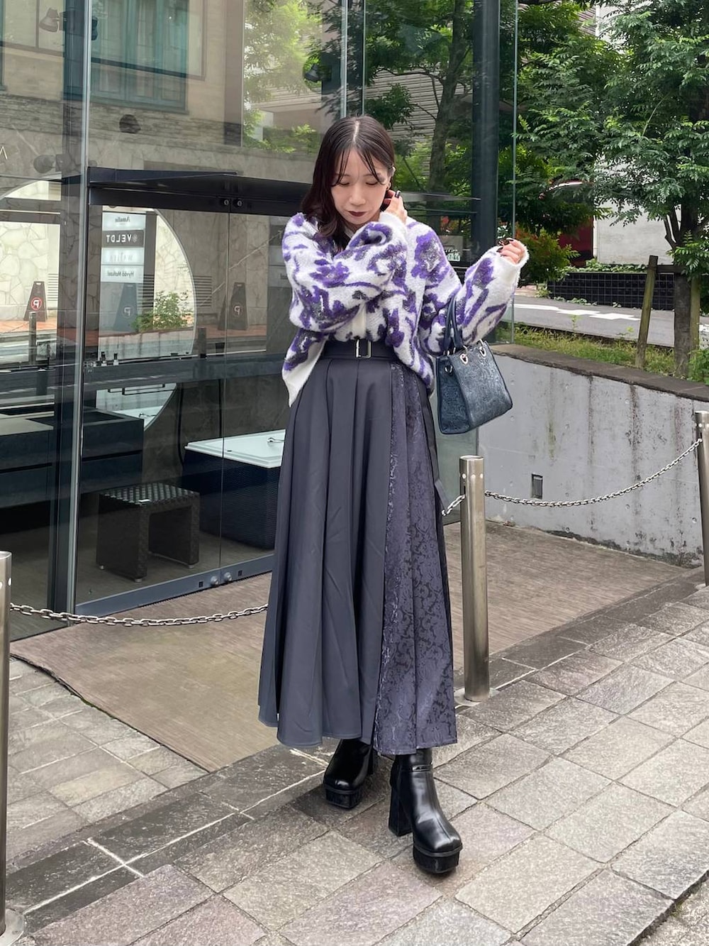 グレー系のショルダーバッグ、ホワイト系のカーディガン/ボレロ、ブラック系のブーツを着用したレディースの秋コーディネートの2枚目の写真