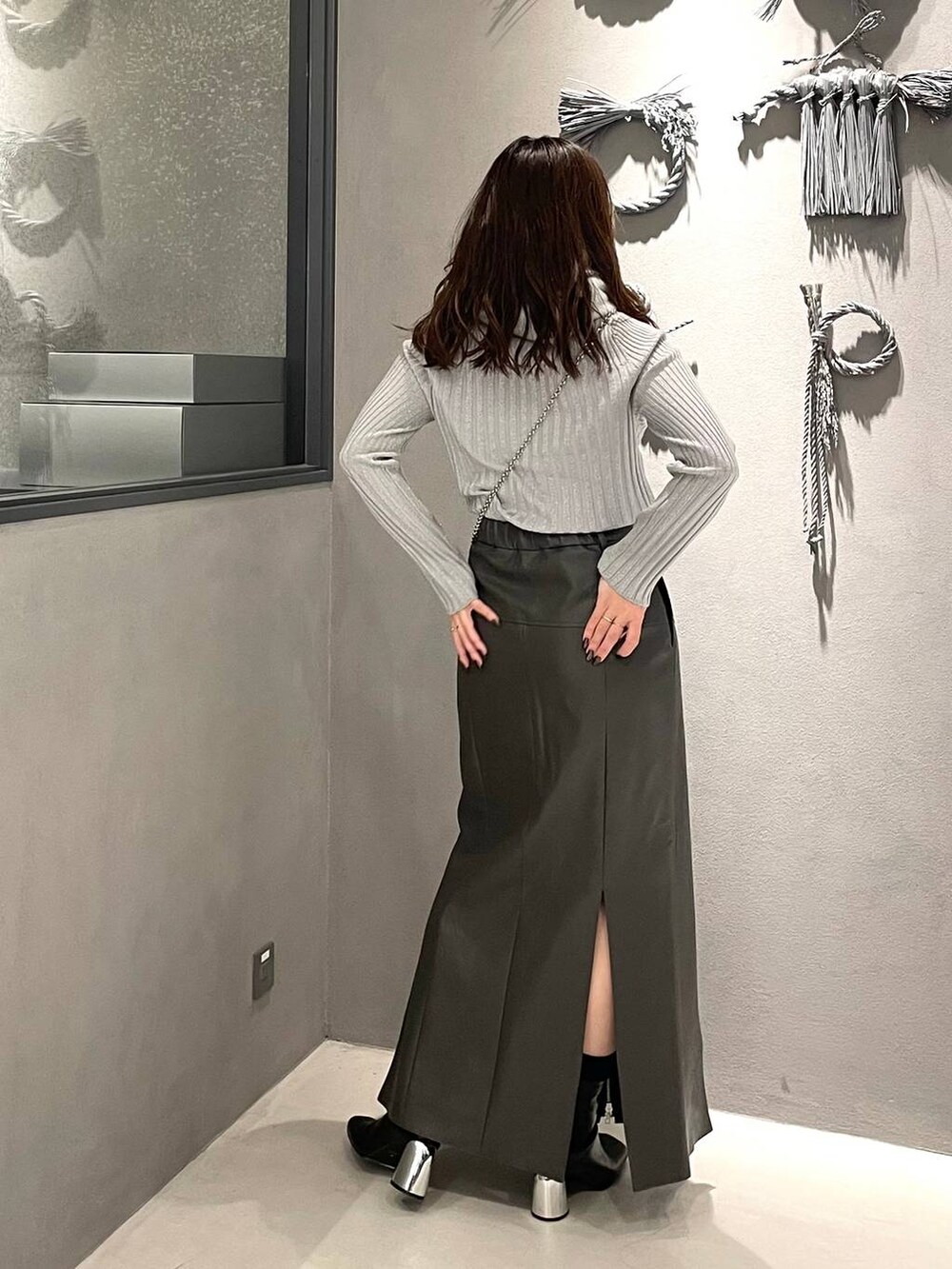 ホワイト系のニット/セーター、ブラック系のブーツ、グレー系のスカートを着用したレディースの冬コーディネートの3枚目の写真