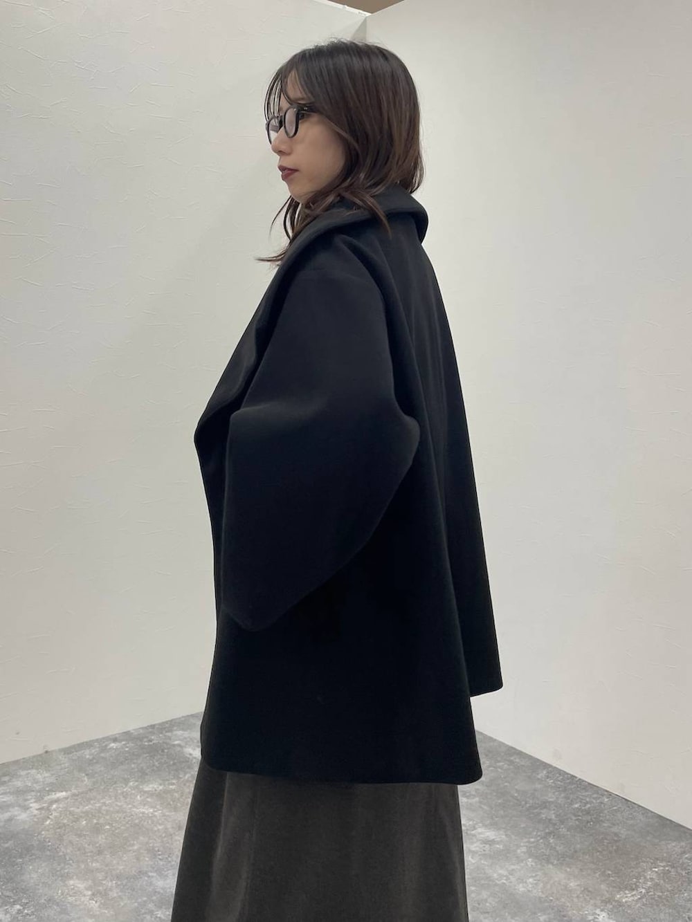 ブラック系のチェスターコート、グレー系のニット/セーター、ブラック系のブーツを着用したレディースの秋コーディネートの8枚目の写真