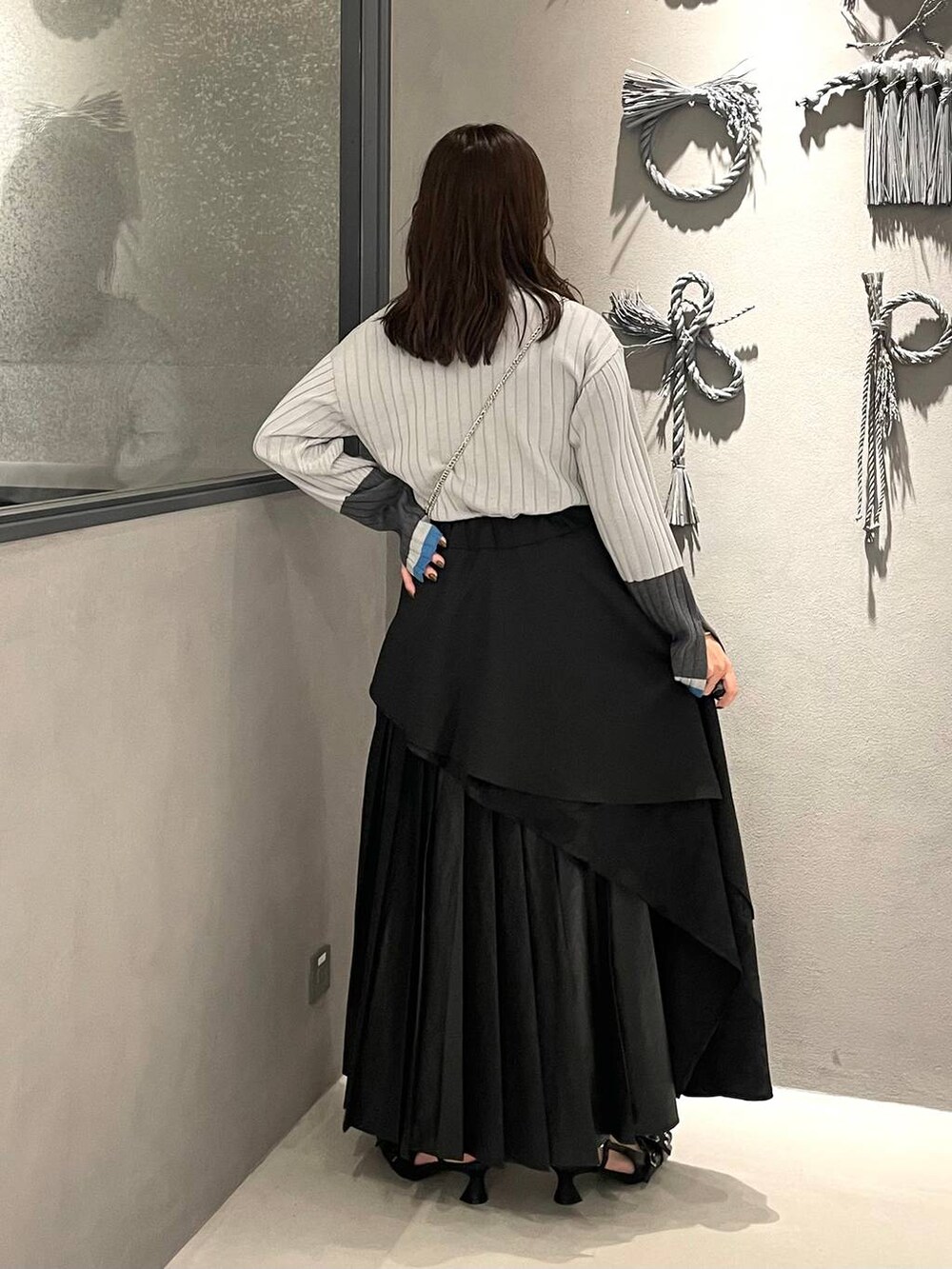 ブラック系のスカート、ブラック系のパンプス、グレー系のニット/セーターを着用したレディースの秋コーディネートの3枚目の写真