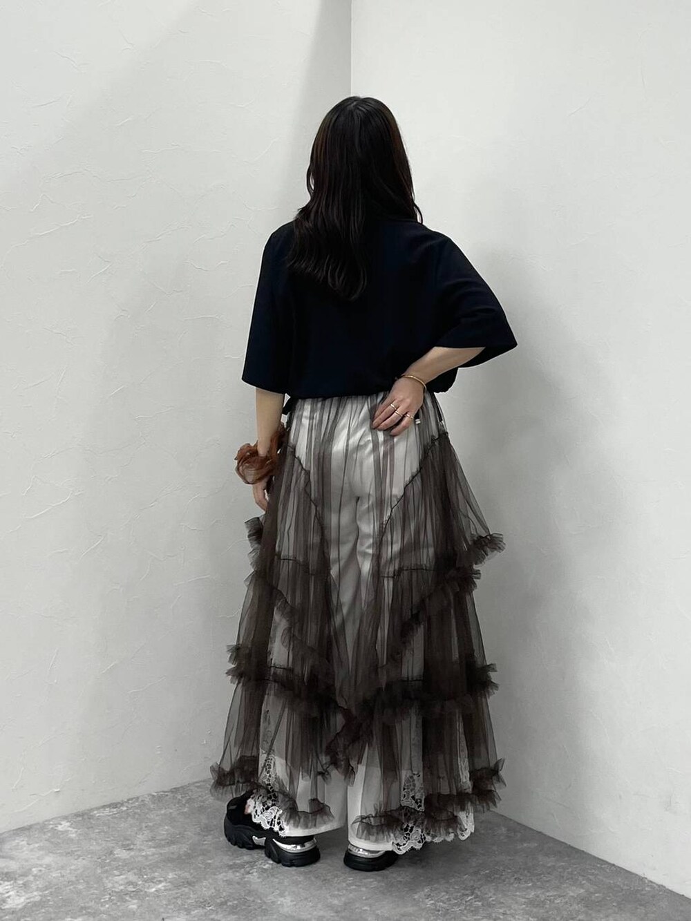 ブラウン系のスカート、ブラック系のサンダル、ホワイト系のその他パンツを着用したレディースの夏コーディネートの3枚目の写真