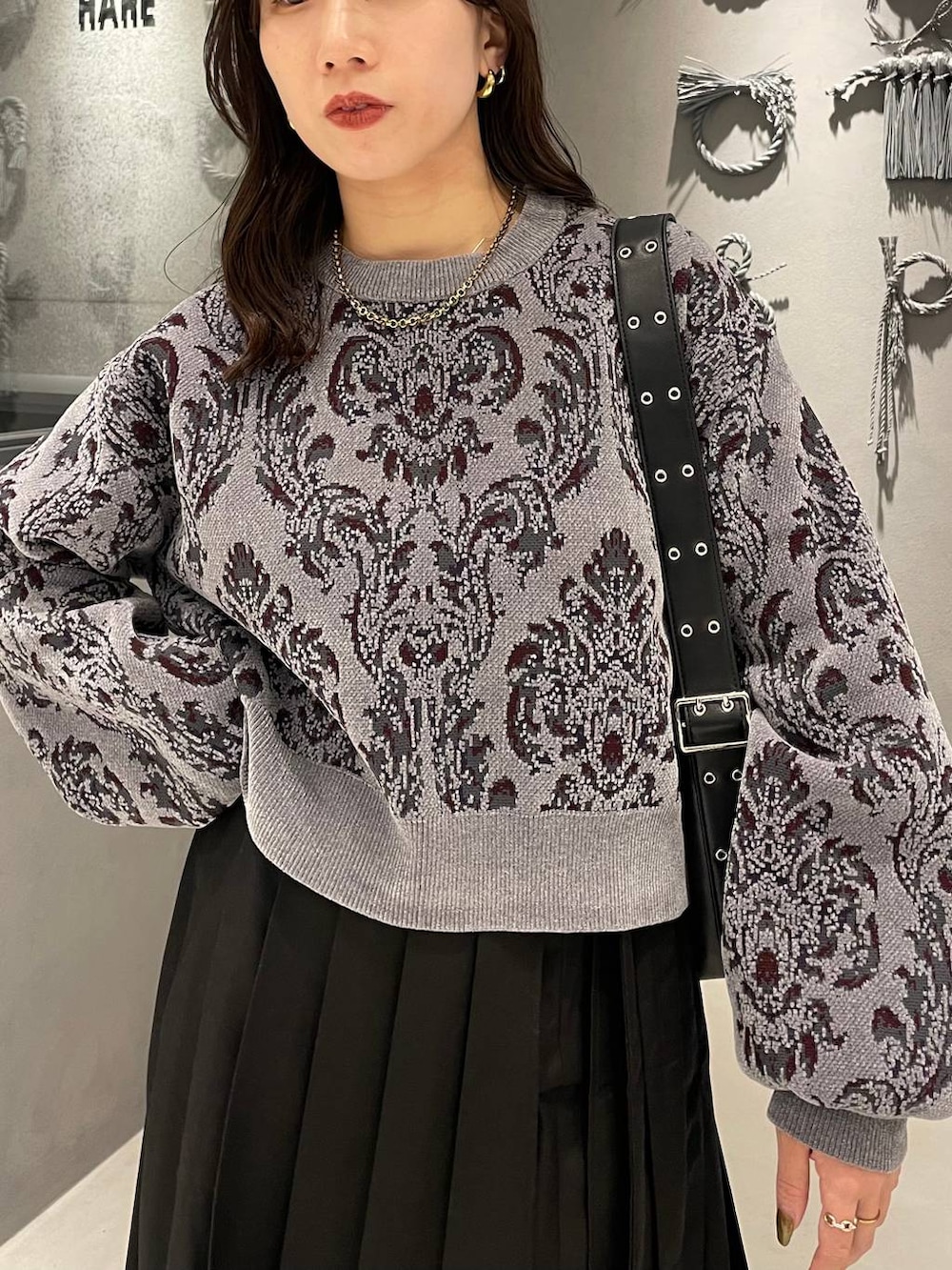 グレー系のニット/セーター、ブラック系のブーツ、ブラック系のショルダーバッグを着用したレディースの秋コーディネートの4枚目の写真