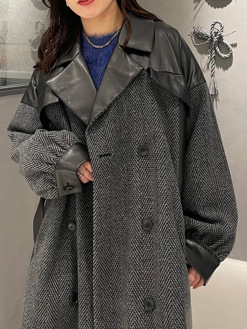 グレー系のチェスターコート、ブラック系のブーツ、ブルー系のニット/セーターを着用したレディースの秋コーディネートの5枚目の写真