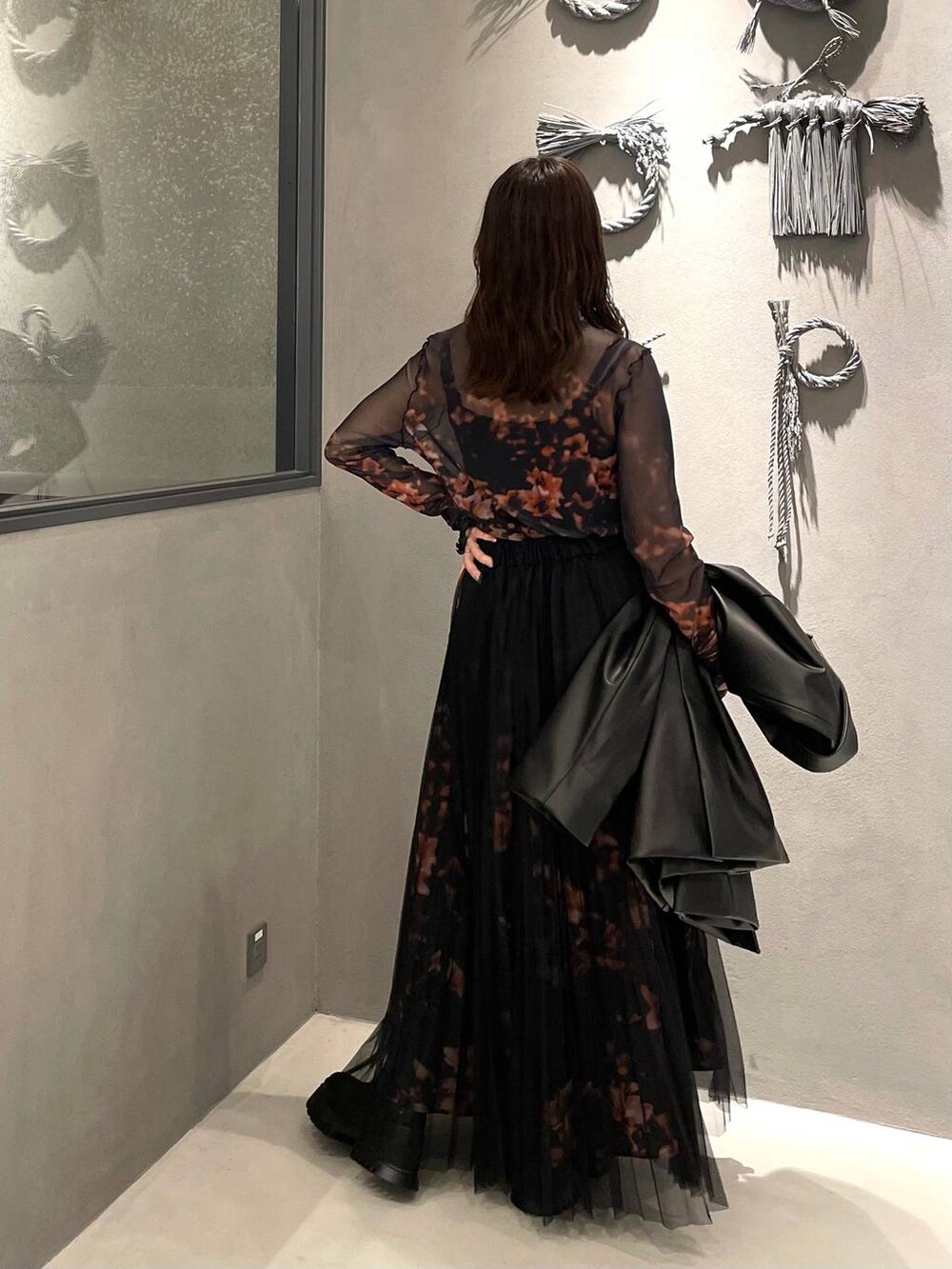 ブラック系のブーツ、オレンジ系のスカート、オレンジ系のTシャツ/カットソーを着用したレディースの秋コーディネートの3枚目の写真