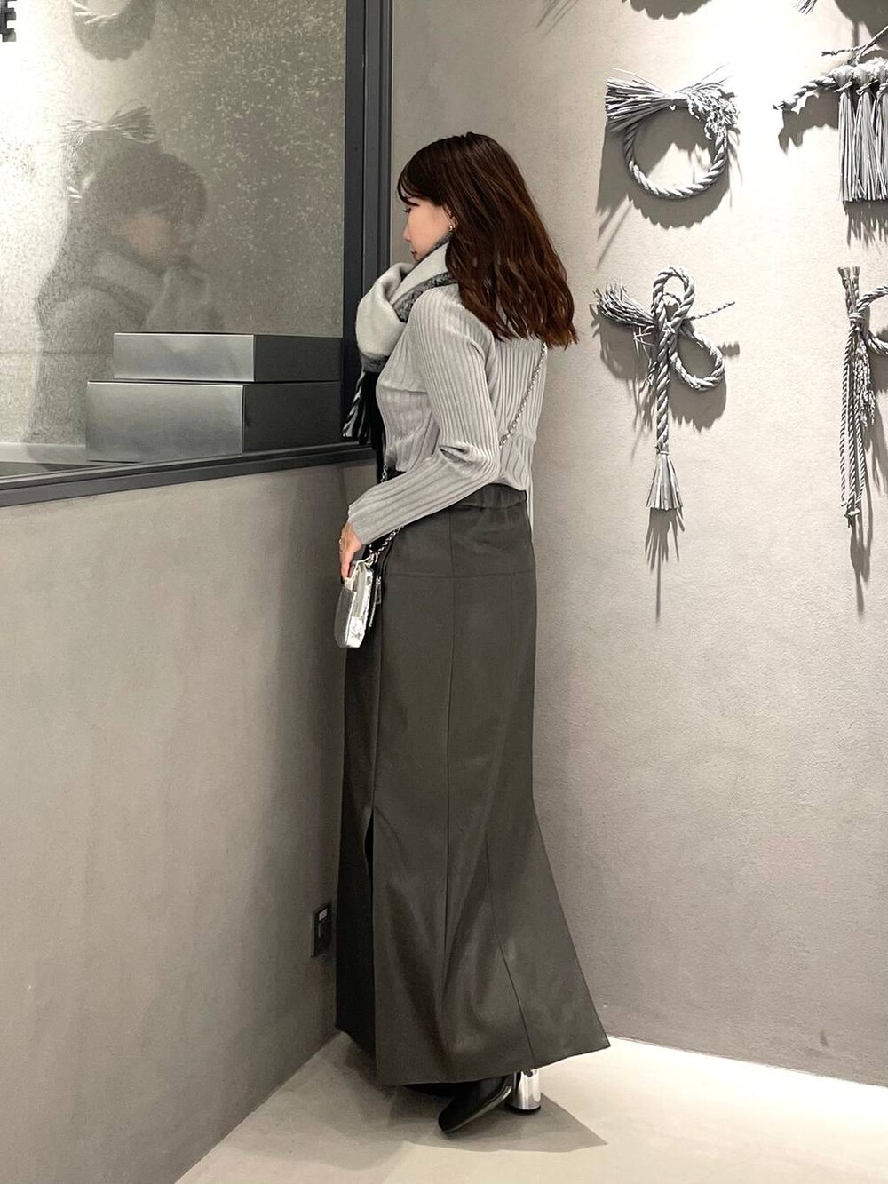 ホワイト系のニット/セーター、ブラック系のブーツ、グレー系のスカートを着用したレディースの冬コーディネートの2枚目の写真