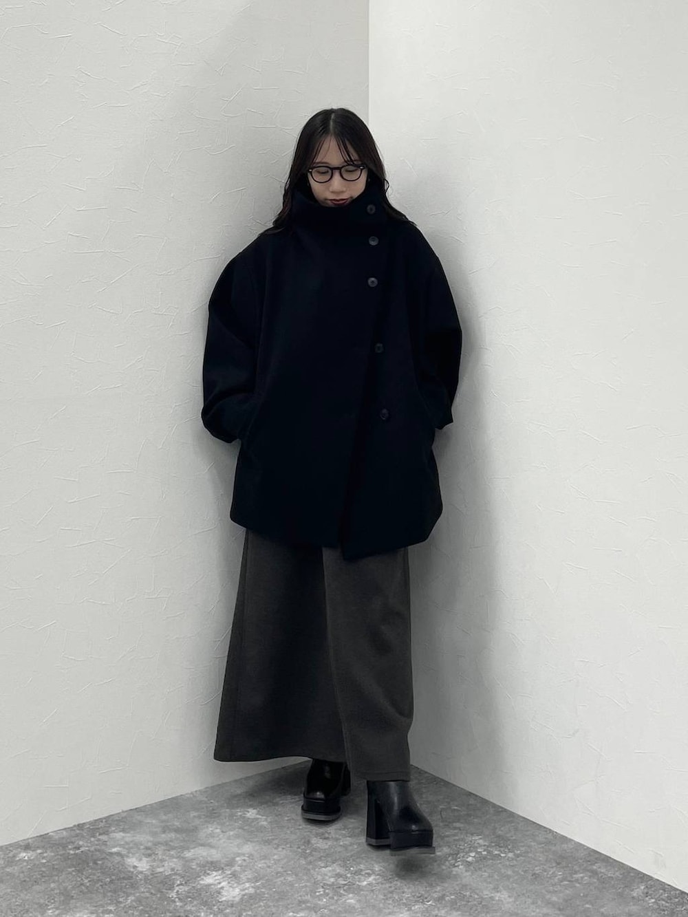 ブラック系のチェスターコート、グレー系のニット/セーター、ブラック系のブーツを着用したレディースの秋コーディネートの5枚目の写真