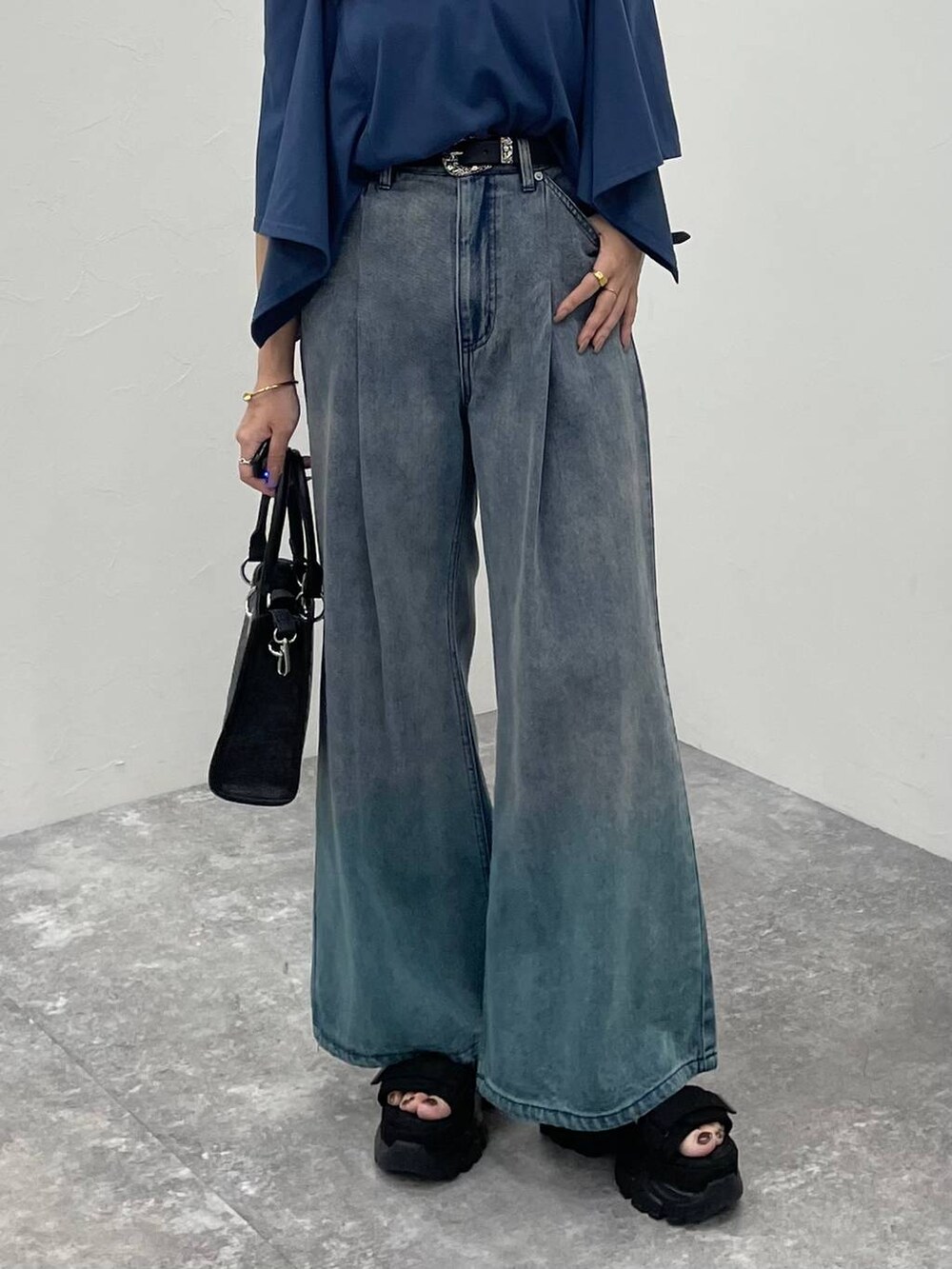 ブルー系のデニムパンツ、ブラック系のショルダーバッグ、ブラック系のサンダルを着用したレディースの夏コーディネートの5枚目の写真