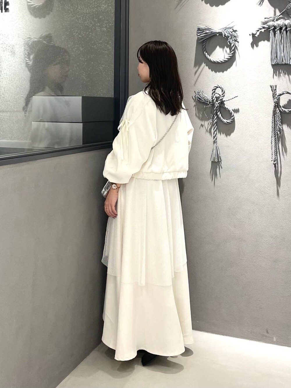 ブラック系のブーツ、ホワイト系のスカート、ホワイト系のブルゾンを着用したレディースの冬コーディネートの2枚目の写真