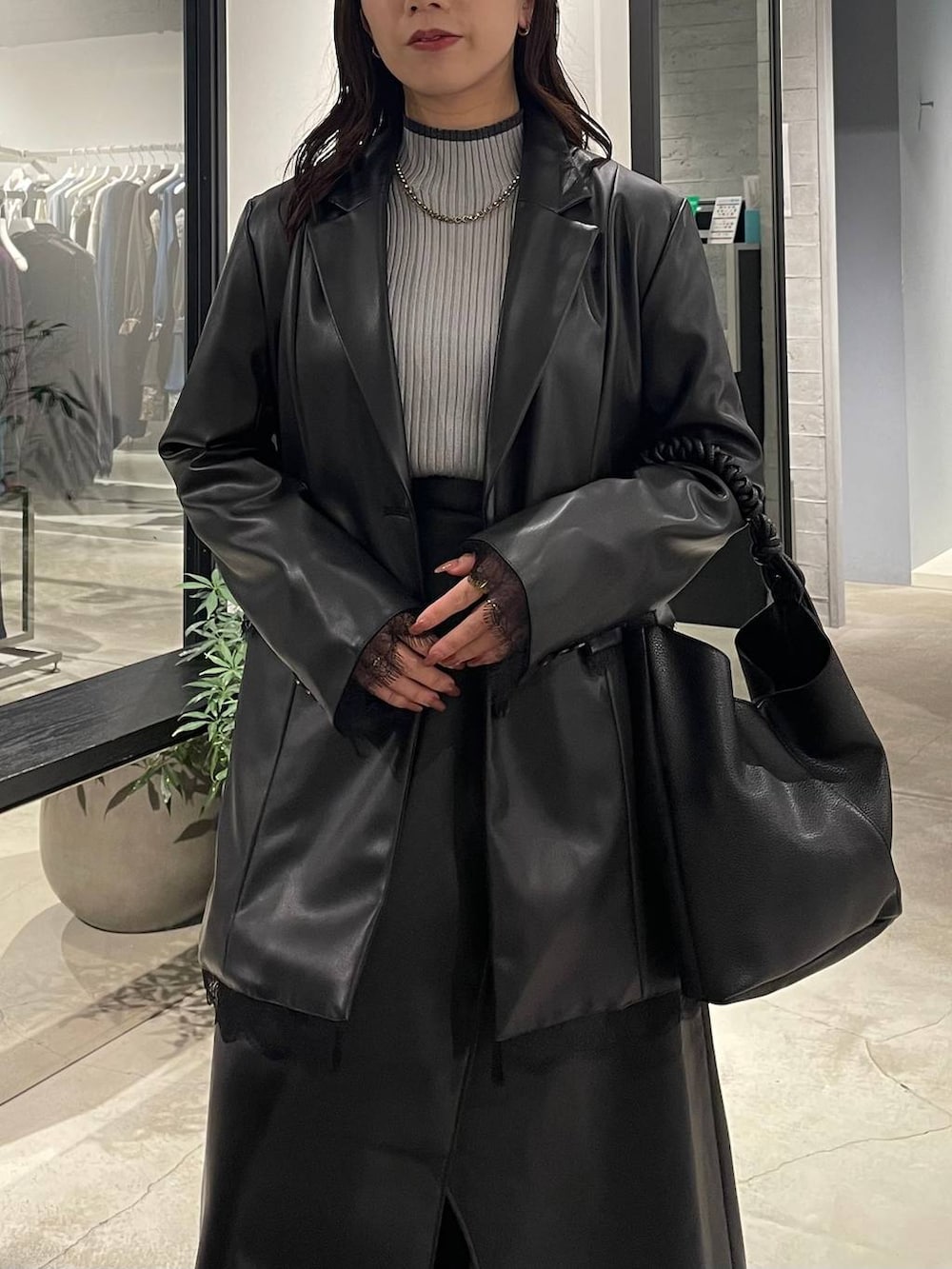 グレー系のニット/セーター、ブラック系のスカート、ブラック系のテーラードジャケットを着用したレディースの秋コーディネートの4枚目の写真