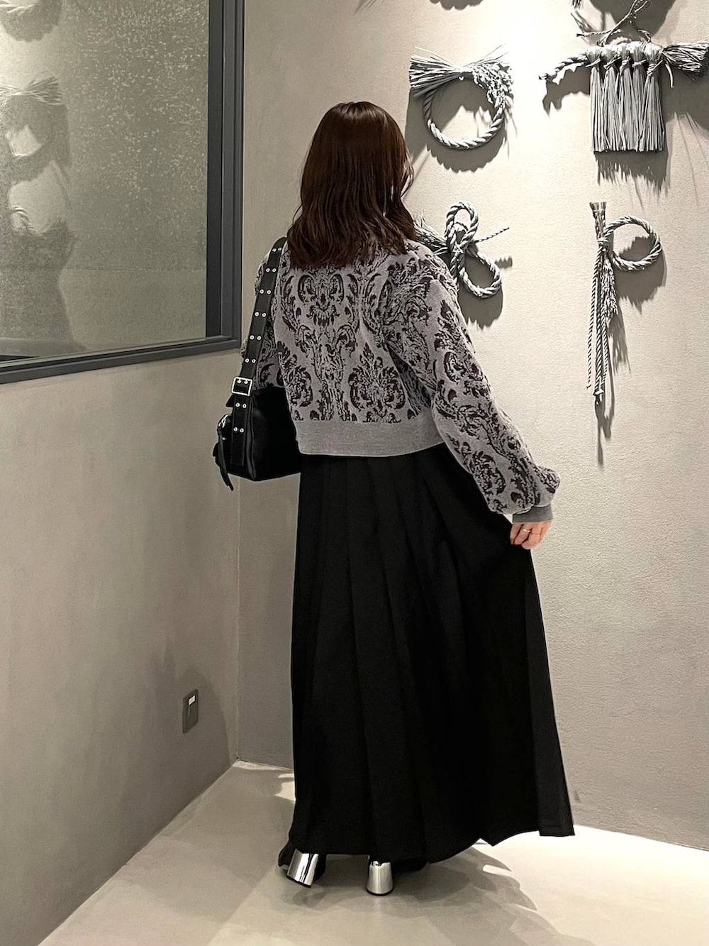 グレー系のニット/セーター、ブラック系のブーツ、ブラック系のショルダーバッグを着用したレディースの秋コーディネートの3枚目の写真