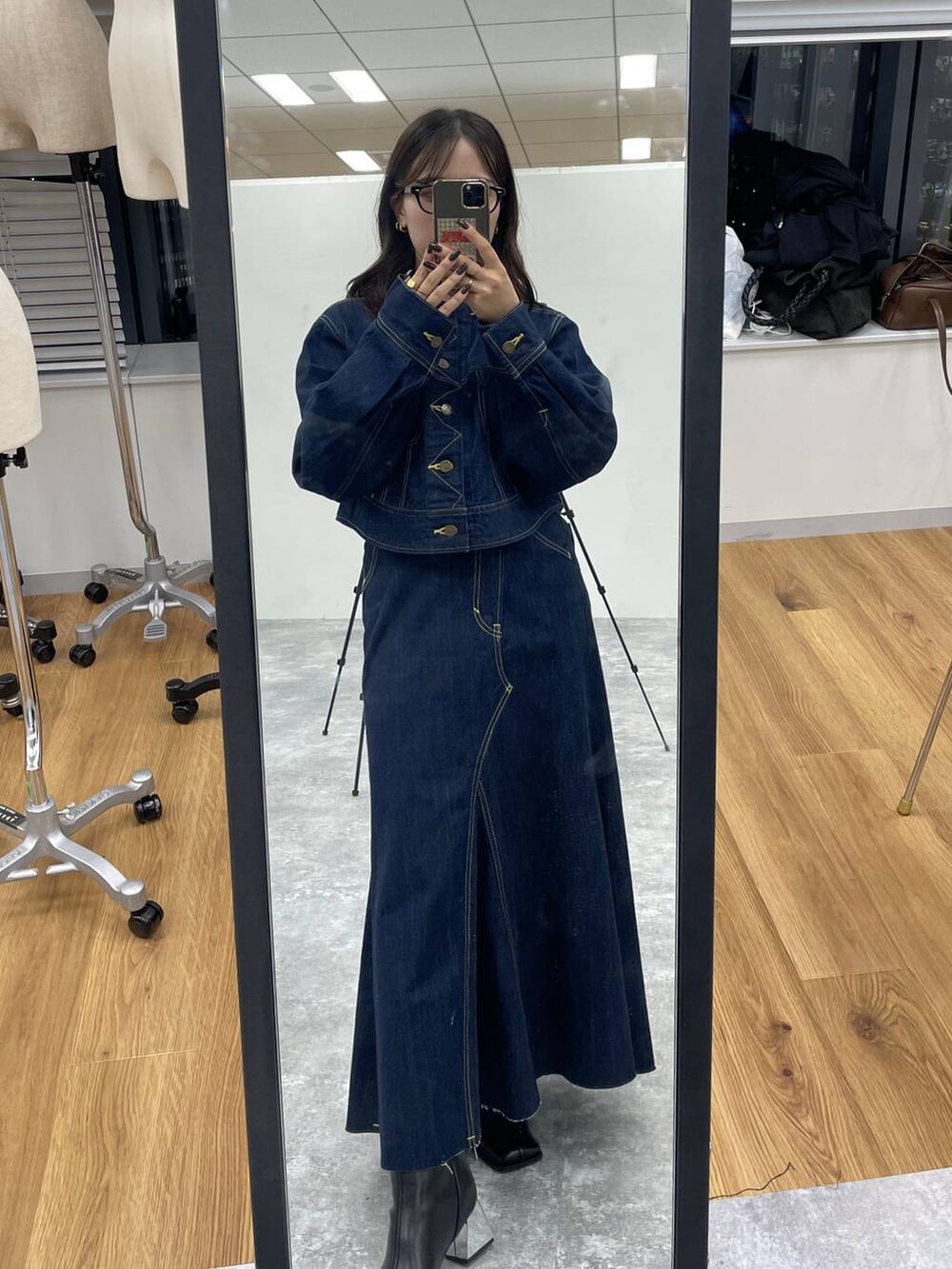 ブルー系のデニムジャケット、ブラック系のブーツ、ブルー系のデニムスカートを着用したレディースの秋コーディネートの2枚目の写真