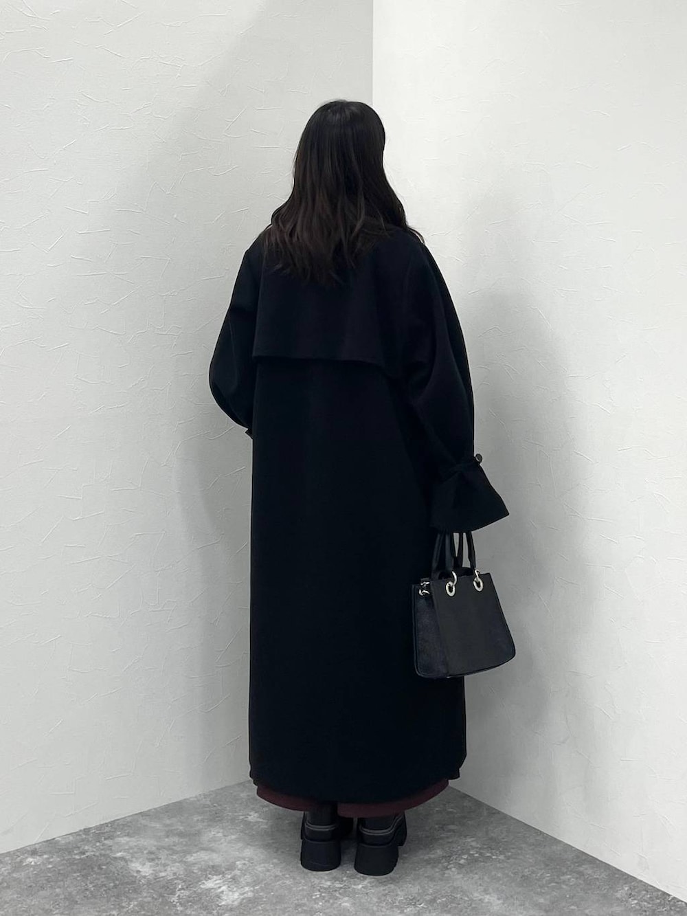 ブラック系のステンカラーコート、ブラック系のショルダーバッグ、レッド系のワンピースを着用したレディースの冬コーディネートの4枚目の写真